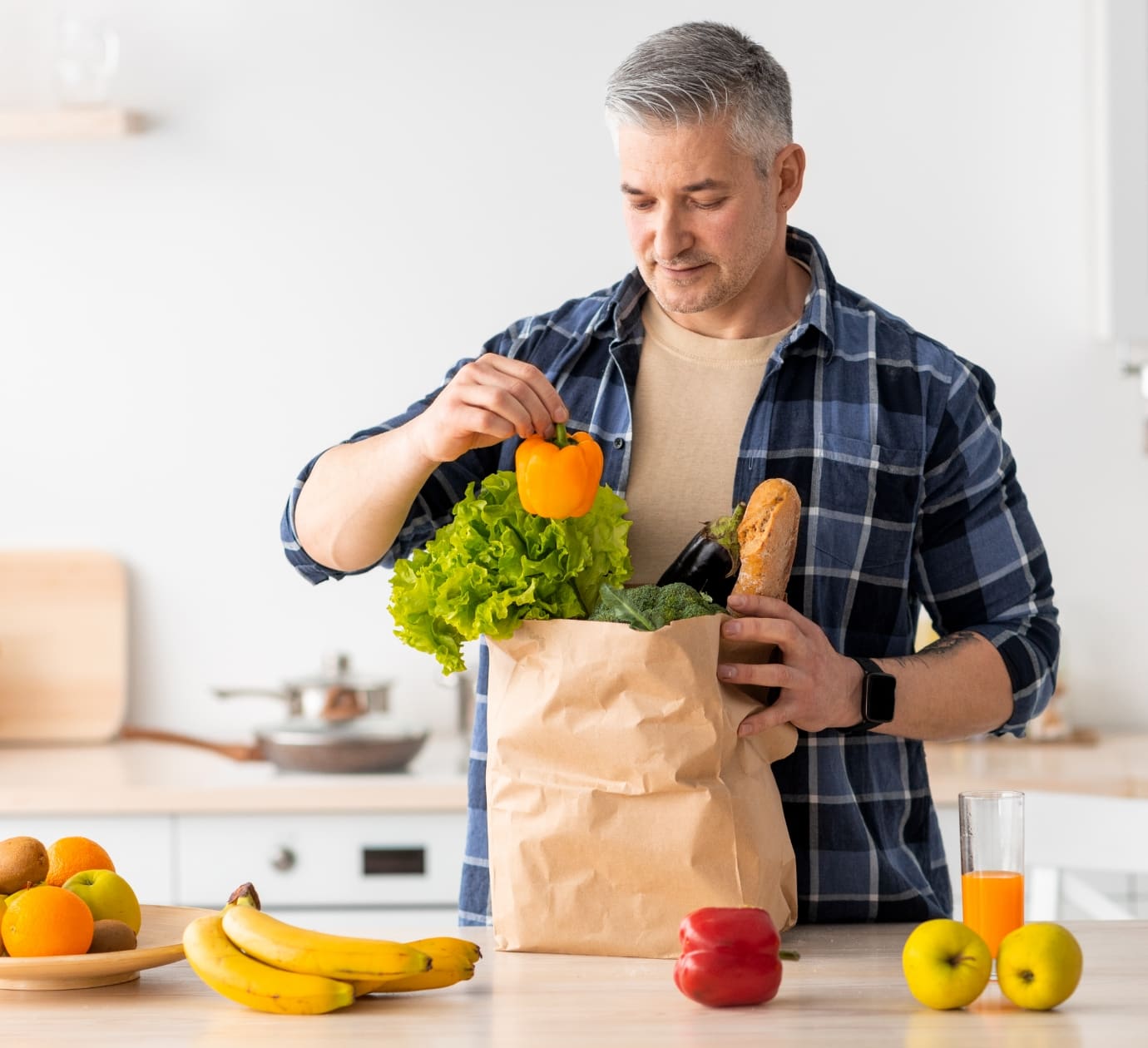Happy senior man unpacking paper bag with grocery ordered from internet.